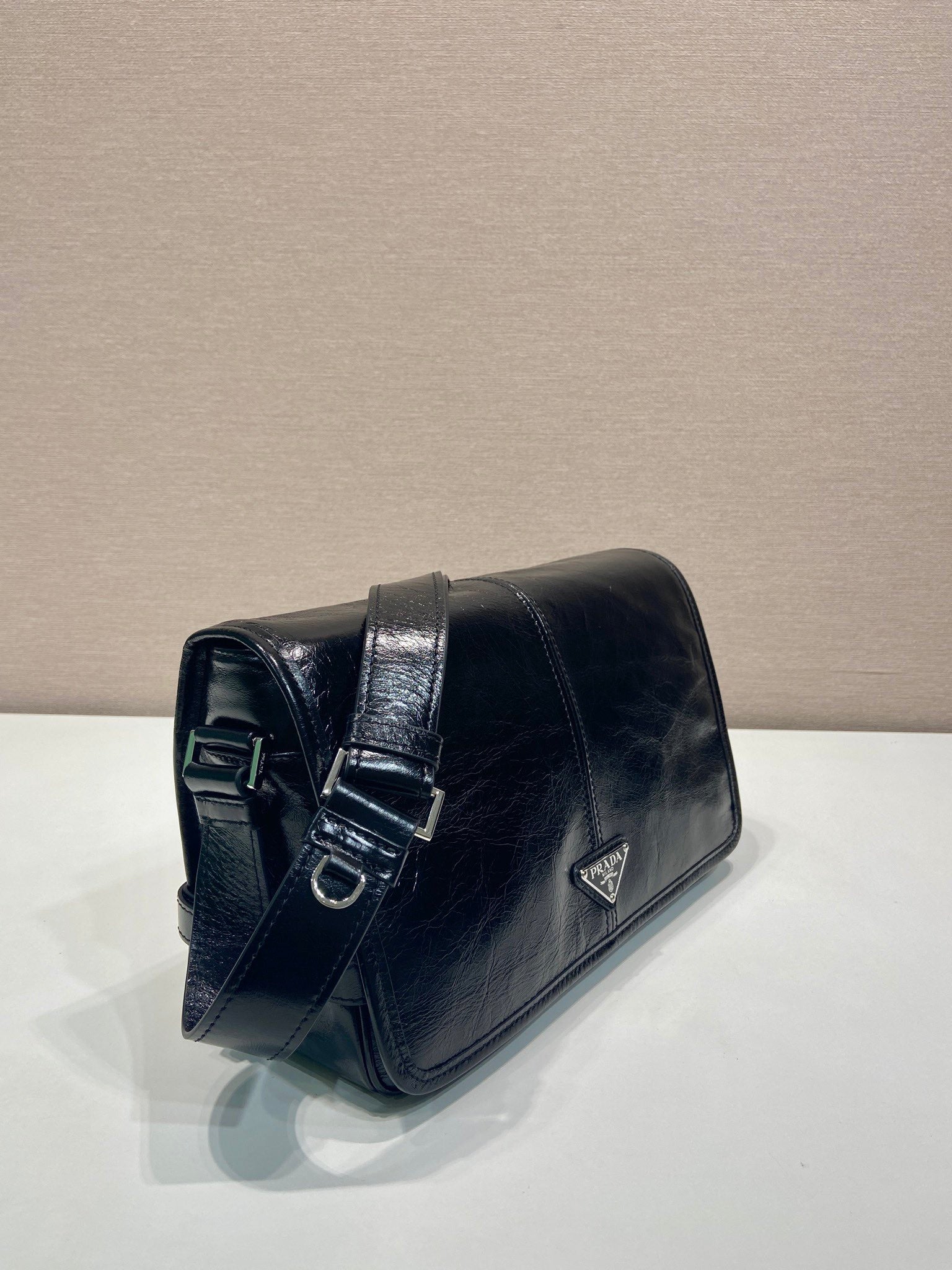 Dark leather flap shoulder bag with buckle strap detail and triangle logo