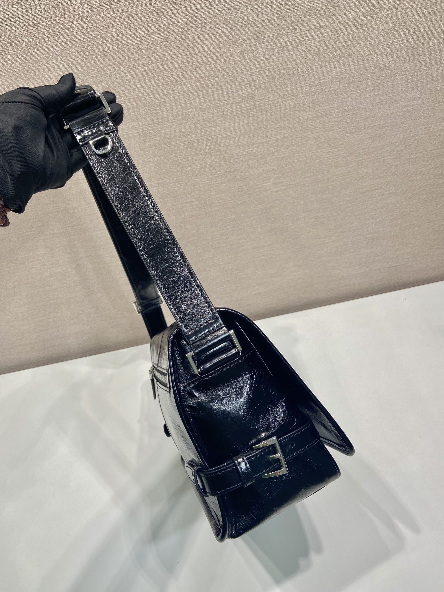 Dark leather mini crossbody bag with metal buckle closure shown by strap