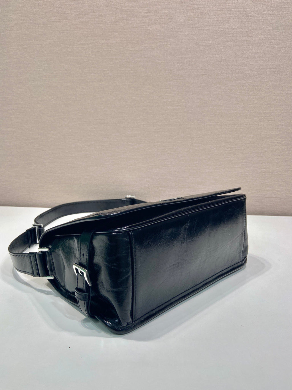 Dark leather top-handle shoulder bag with curved shape and strap buckle