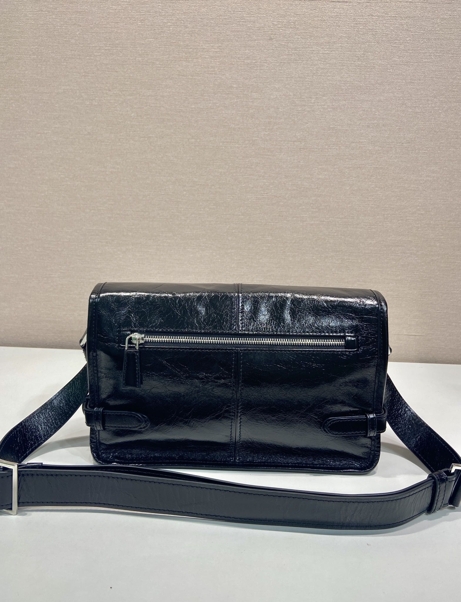 Dark leather crossbody bag with top zip and adjustable shoulder strap