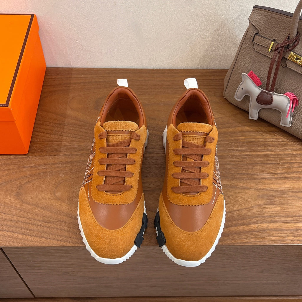 Hermes unisex sneakers in tan suede with orange laces and white sole, side view