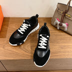 Pair of black Hermes unisex sneakers with white laces and thick tread sole