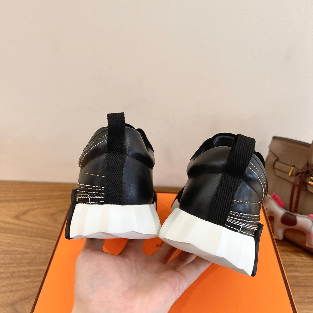 Back view of black Hermes unisex sneakers with stacked heel and white tread sole