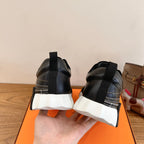 Back view of black Hermes unisex sneakers with stacked heel and white tread sole