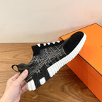 Black Hermes unisex sneaker with geometric side panel and ribbed white sole edge