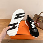 Black Hermes unisex sneaker with white lace-up front and contrasting white outsole
