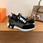 Black Hermes unisex sneakers with white lace-up closure, patterned side panels, white tread