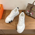 Hermes unisex sneakers, white lace-up with black outsole, side view pair