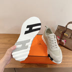 White sneakers with bold striped outsole tread and cushioned lace-up upper.