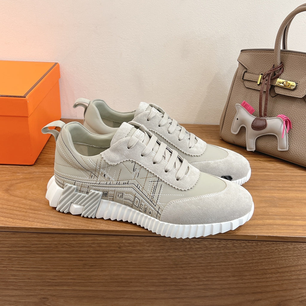 White lace-up sneakers with embossed geometric logo pattern and chunky ribbed sole.