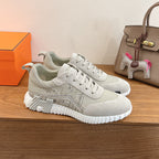 White lace-up sneakers with embossed geometric logo pattern and chunky ribbed sole.