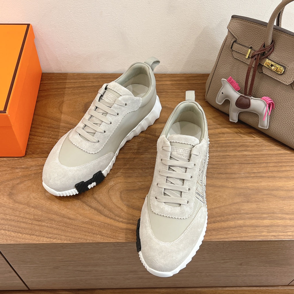 White lace-up sneakers with suede panels, perforated detailing, and textured rubber sole tread.