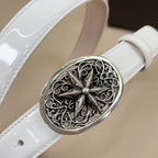 Ornate silver oval belt buckle with floral filigree on white leather strap