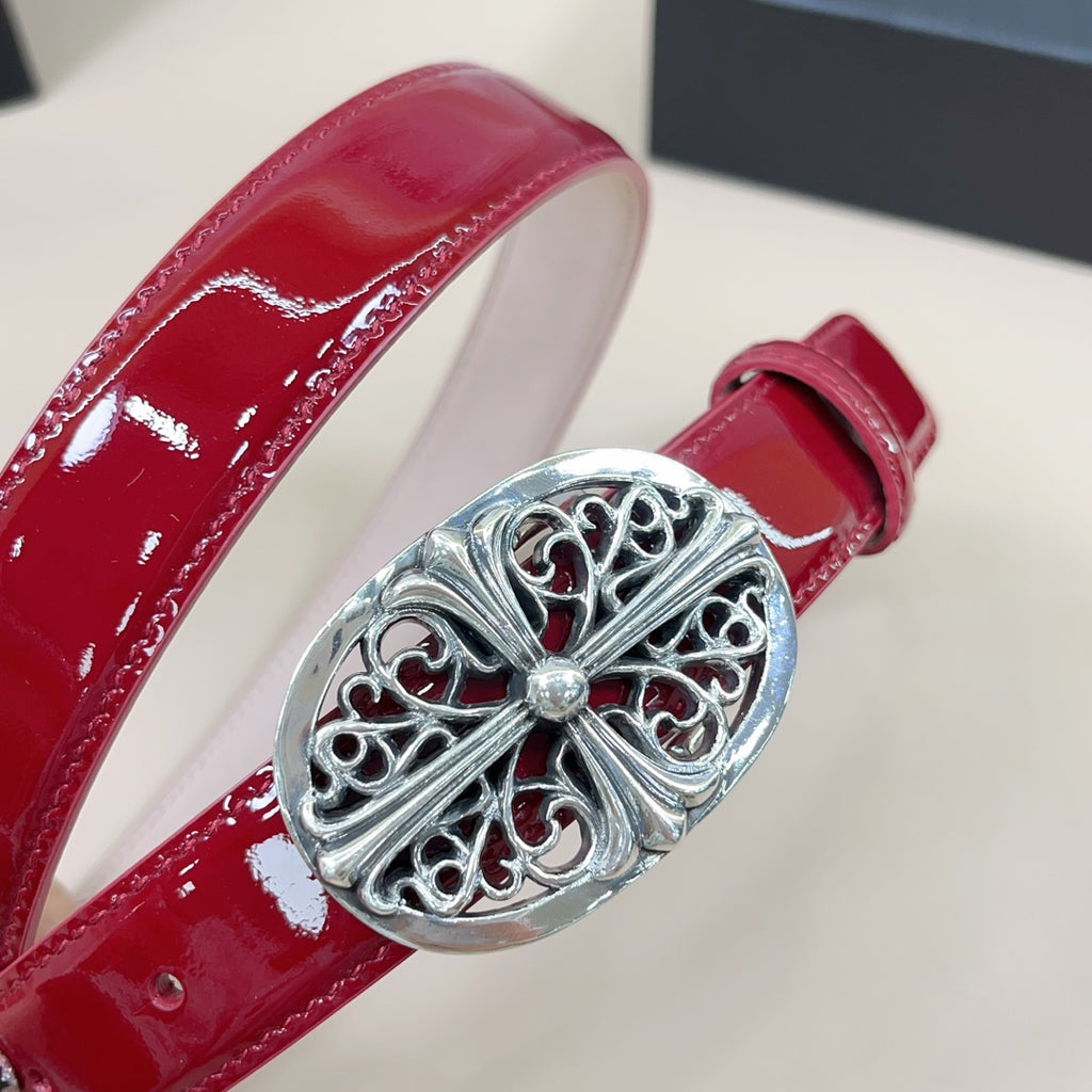 Red patent leather belt close-up with oval silver filigree buckle and center gem