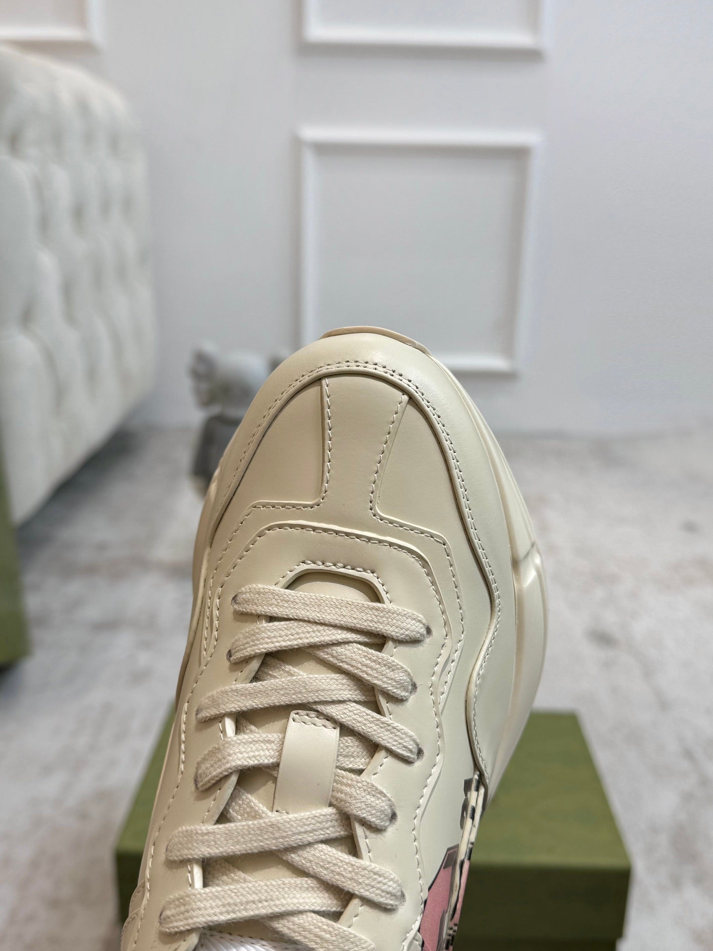 Light beige lace-up sneaker front with visible stitching and eyelets