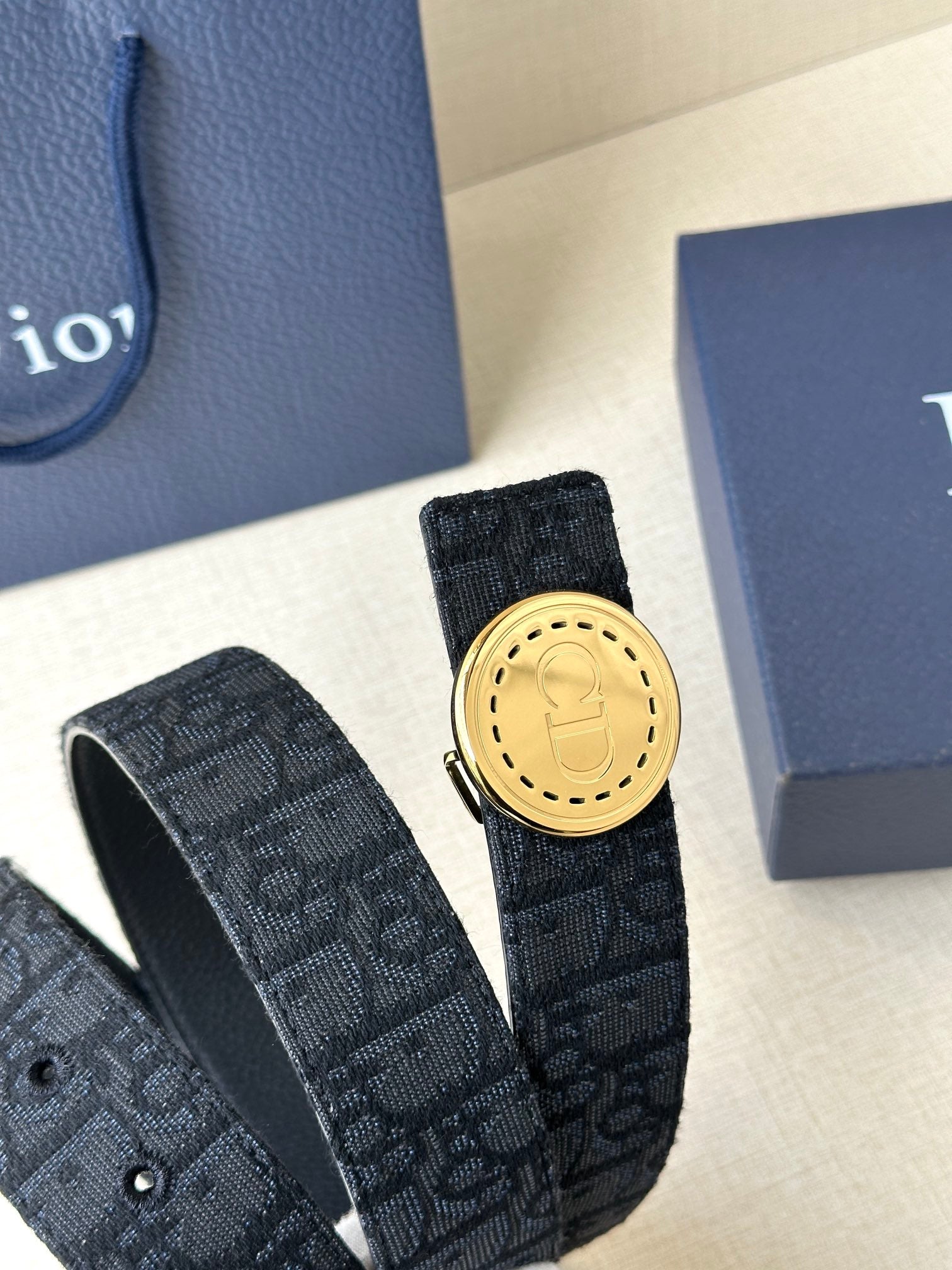 Dior belt detail with dark monogram strap and gold-tone round buckle