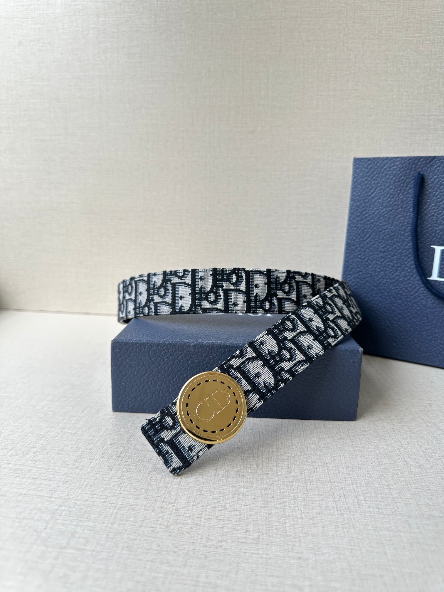 Logo-print belt with tan round buckle, black-and-white patterned strap