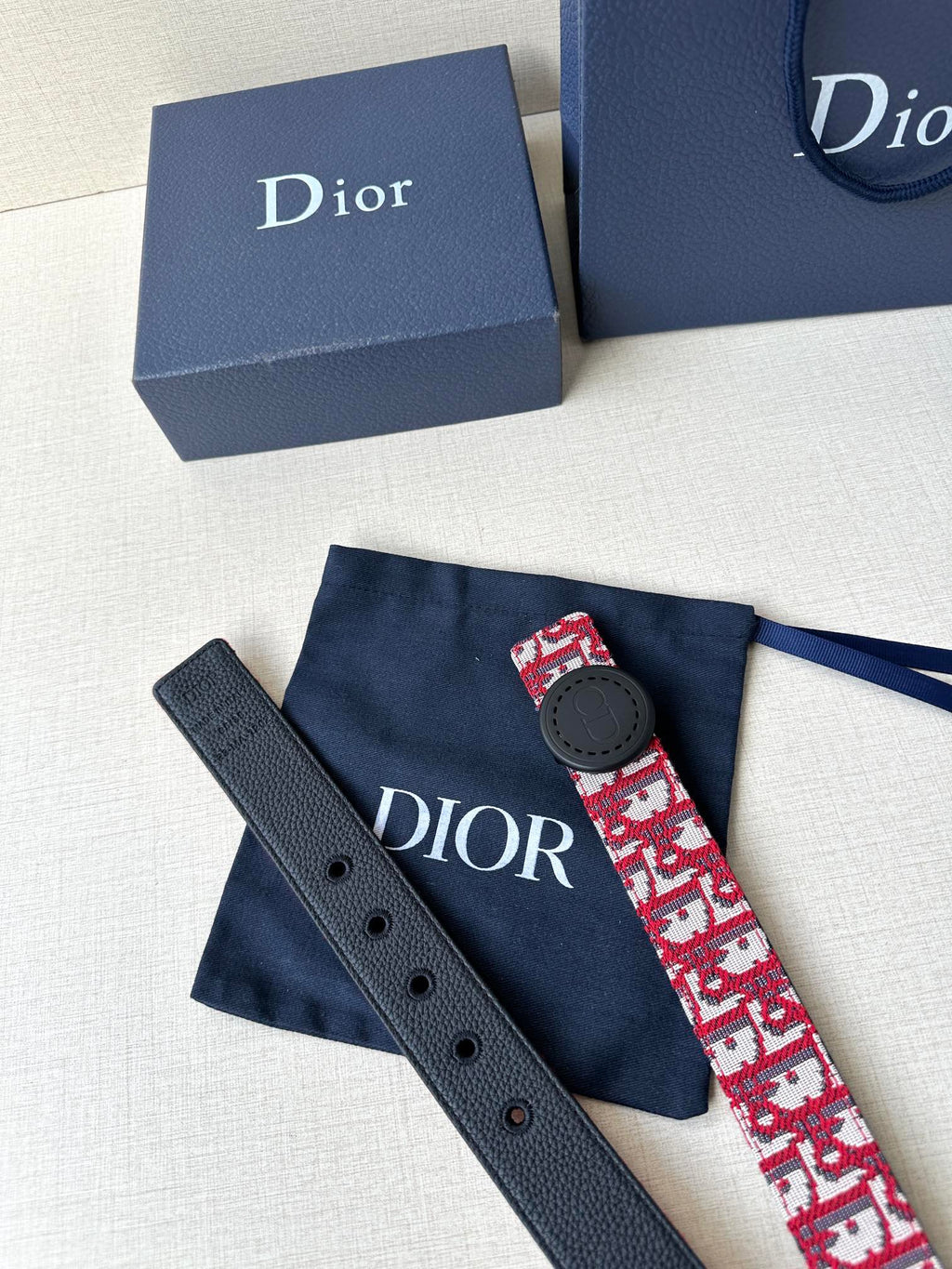 Dior belt and matching navy strap segment; red-and-white monogram with dark round buckle