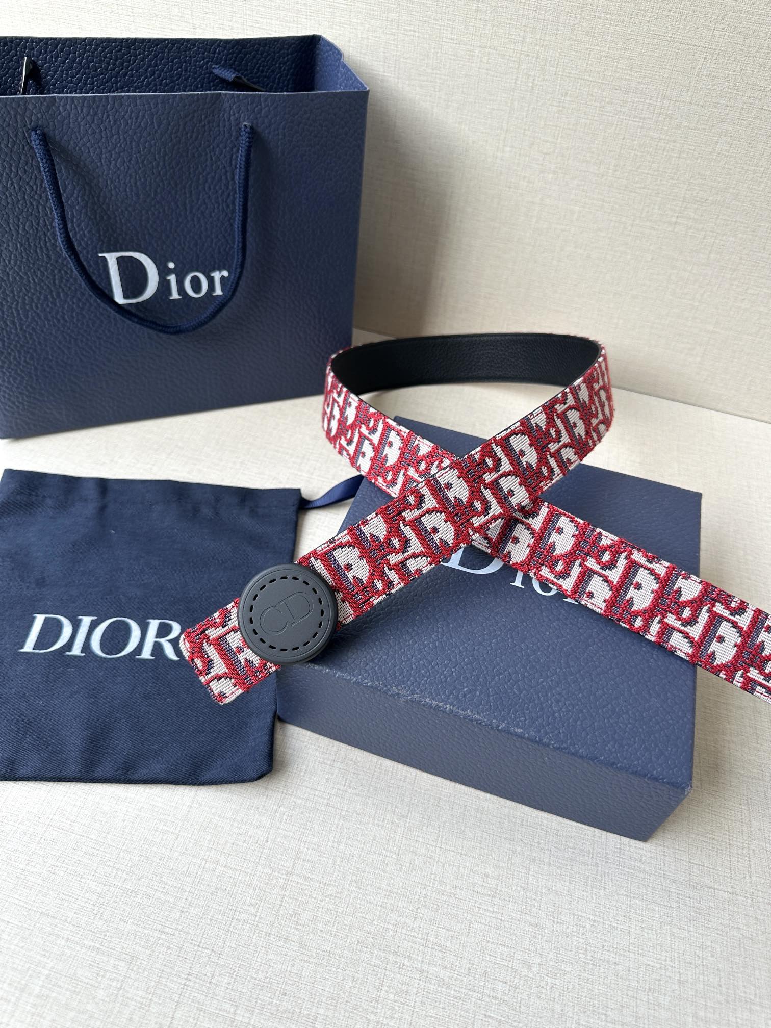 Dior belt with red-and-white monogram strap, black buckle, and black leather strap end