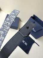 Dior belt with textured navy leather strap and dark keeper, laid on a box