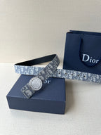 Dior belt with monogram strap and round silver-tone buckle beside gift box