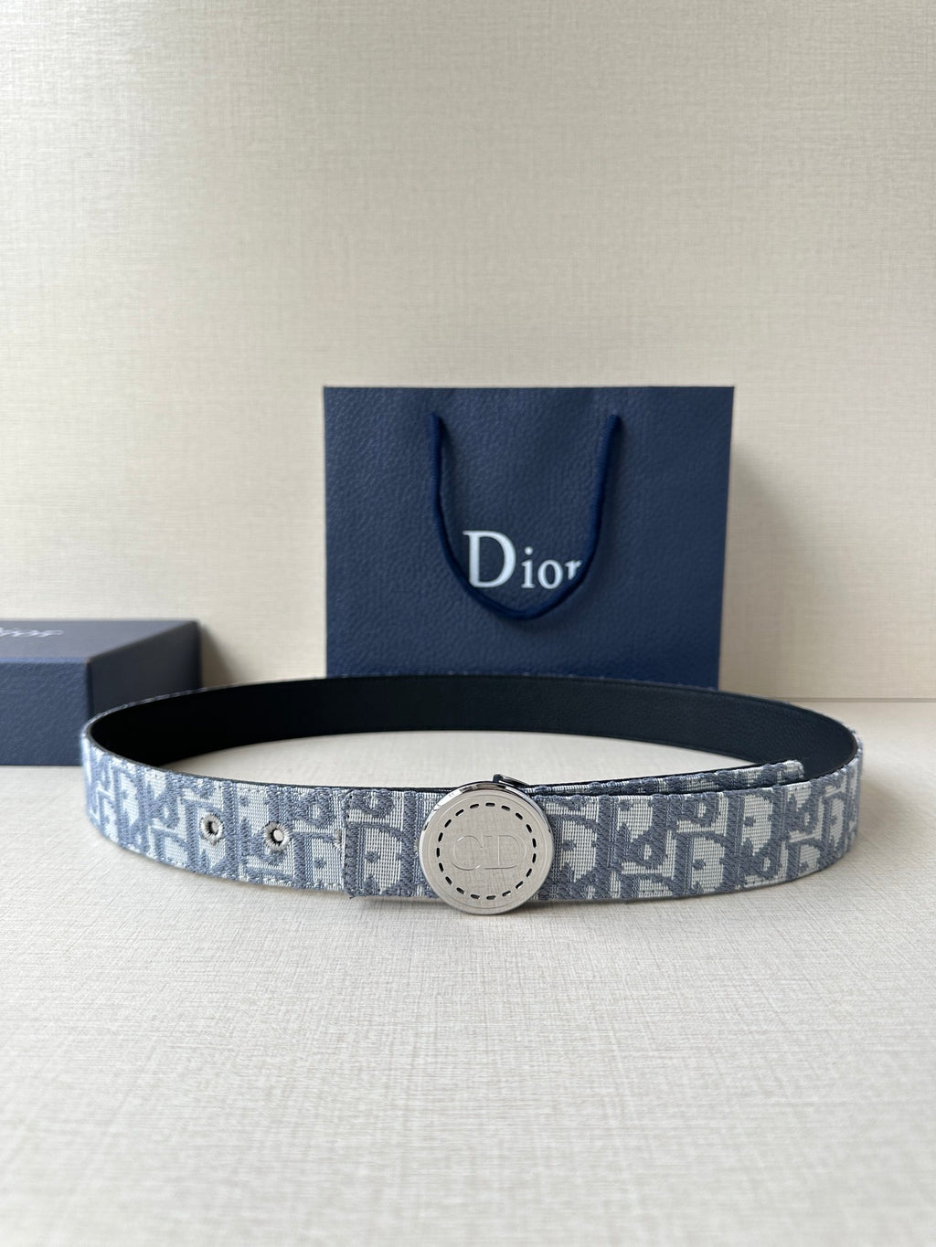 Dior belt with blue-gray monogram pattern and round metal buckle on dark strap