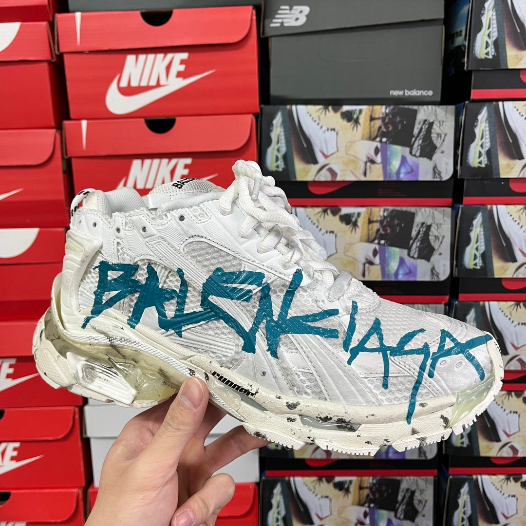 White high-top sneaker with blue graffiti-style logo and lace-up design