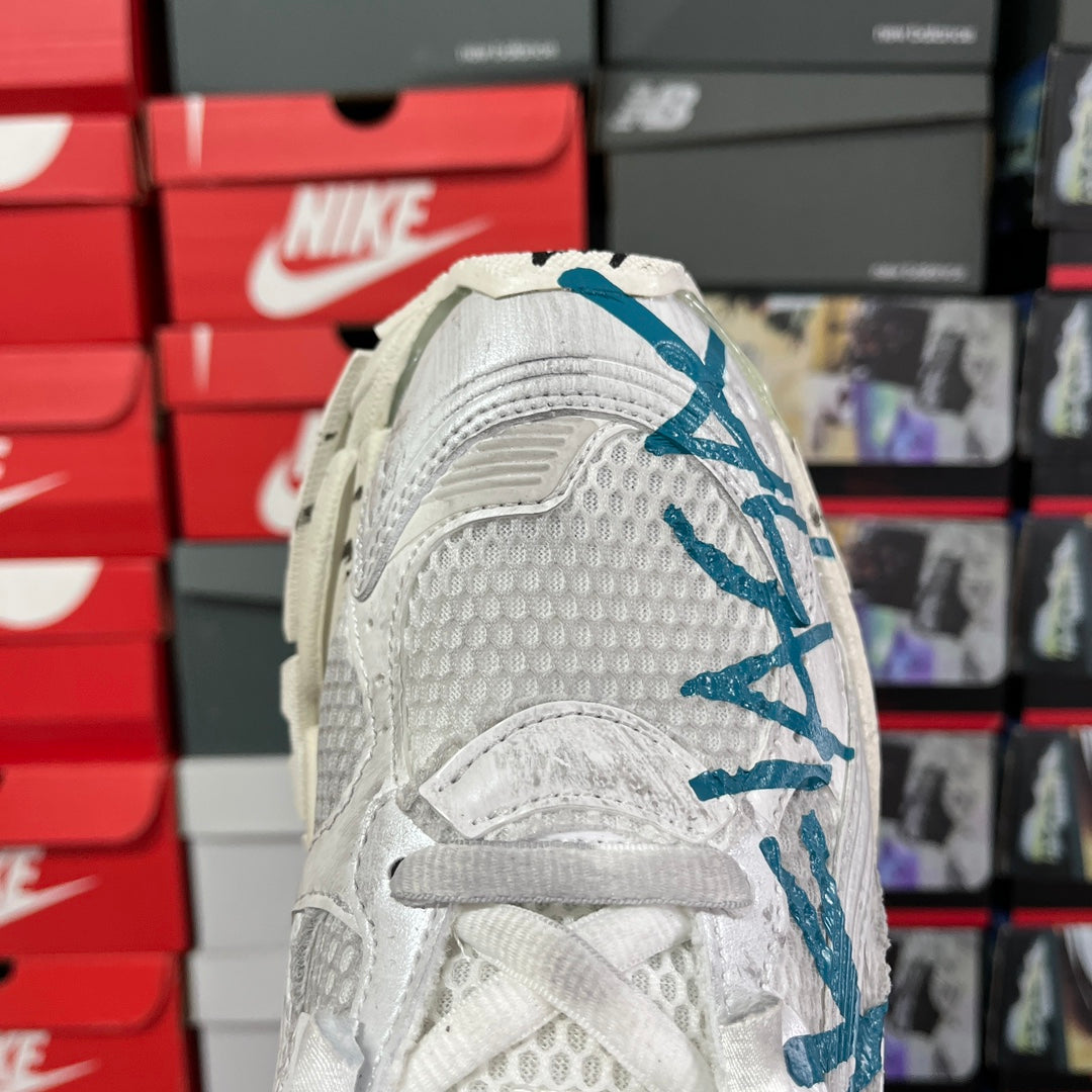 White sneaker quarter panel with embossed texture and blue logo detail