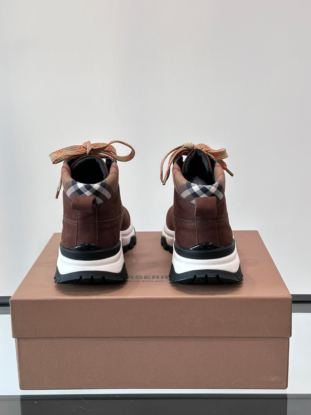 Back view of brown high-top sneakers with plaid heel lining and white rubber sole