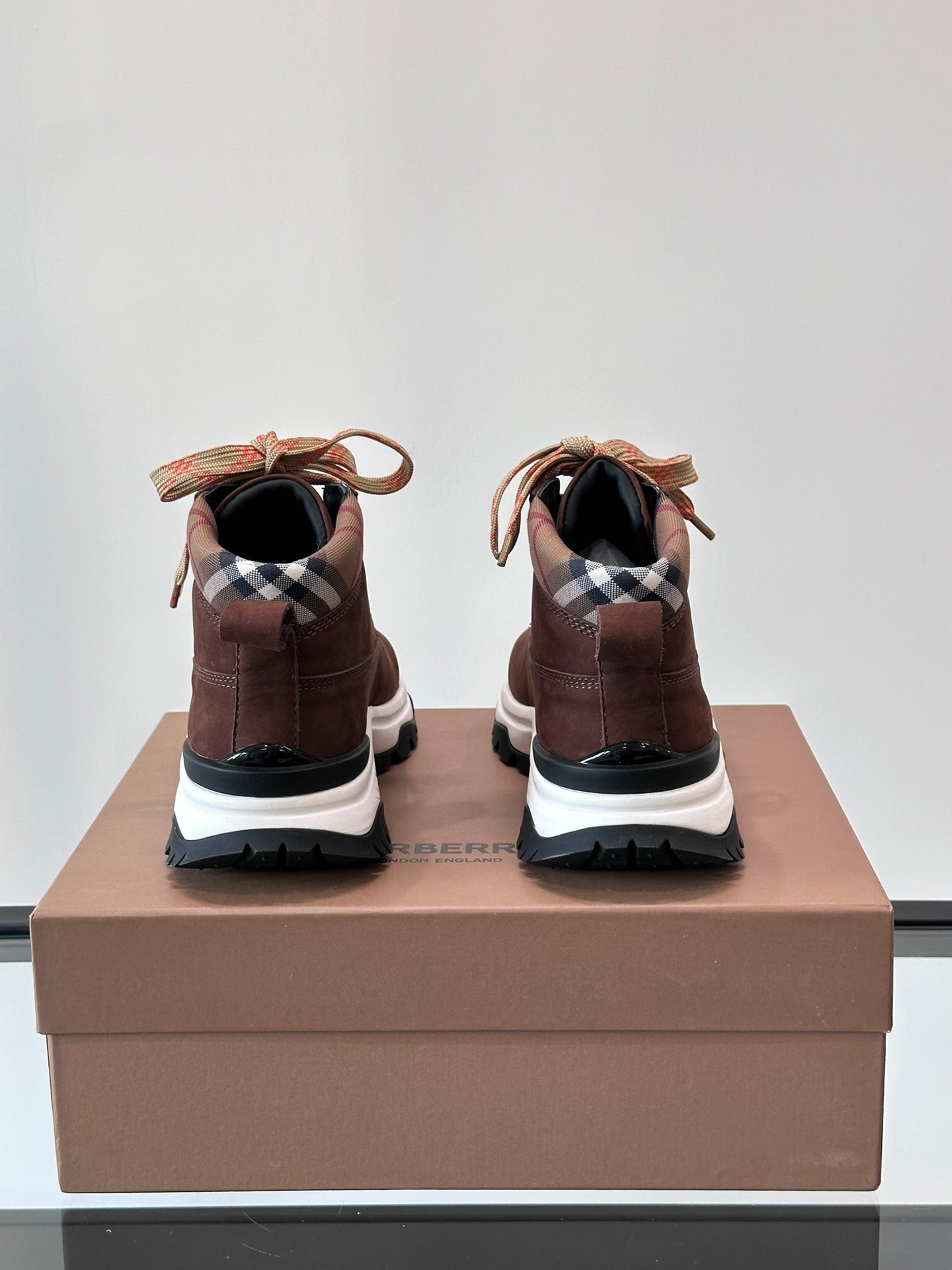 Back view of brown high-top sneakers with plaid heel lining and white rubber sole