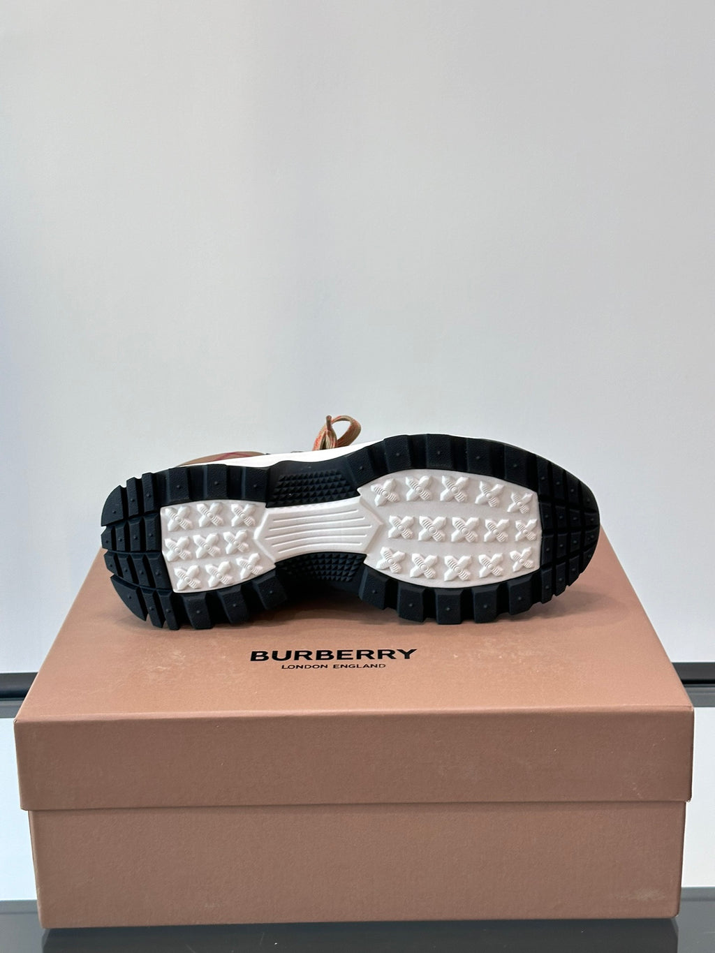 Outsoles of brown sneakers with black-and-white tread and Burberry logo on box