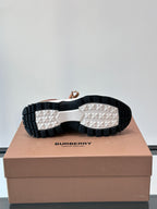 Outsoles of brown sneakers with black-and-white tread and Burberry logo on box