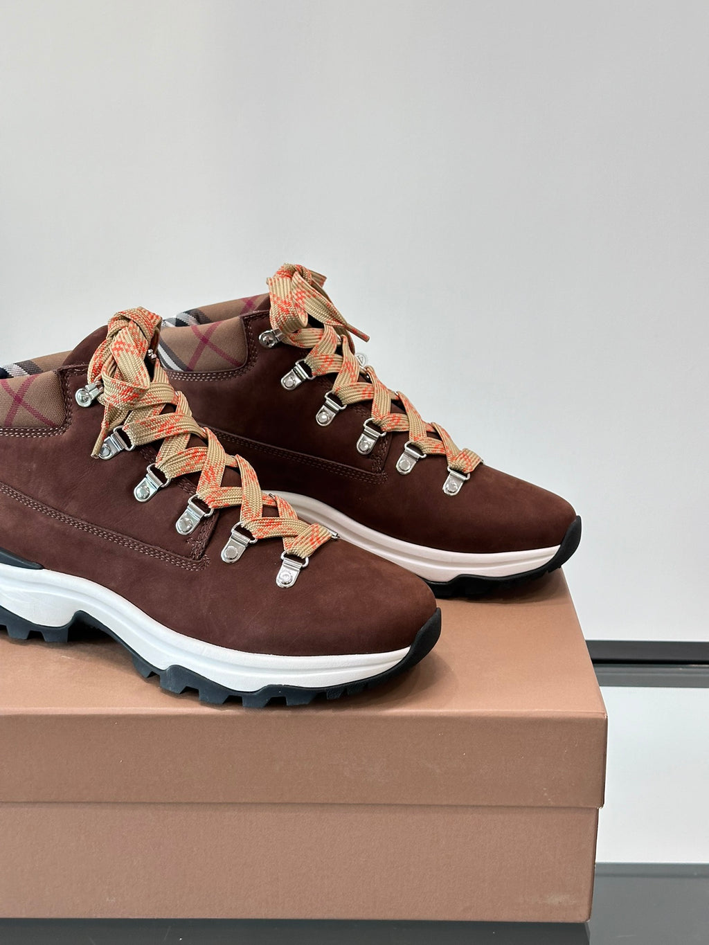 Close-up of brown suede sneakers with lace-up plaid ribbon laces and white sole edge