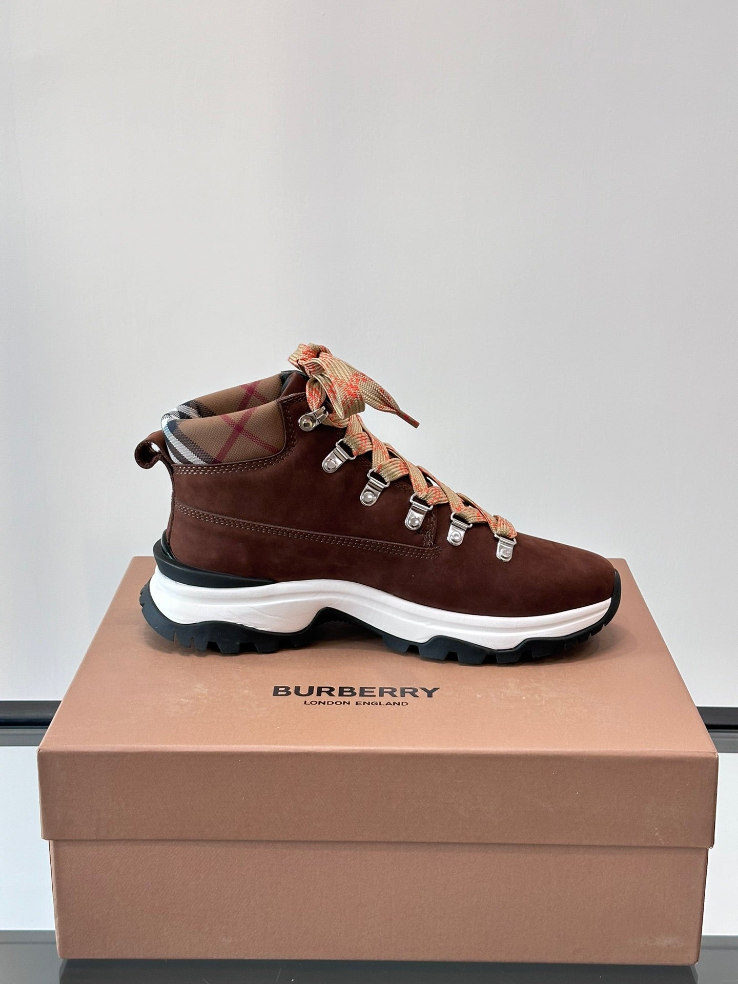 Brown suede high-top sneakers with orange plaid laces and scalloped white outsole
