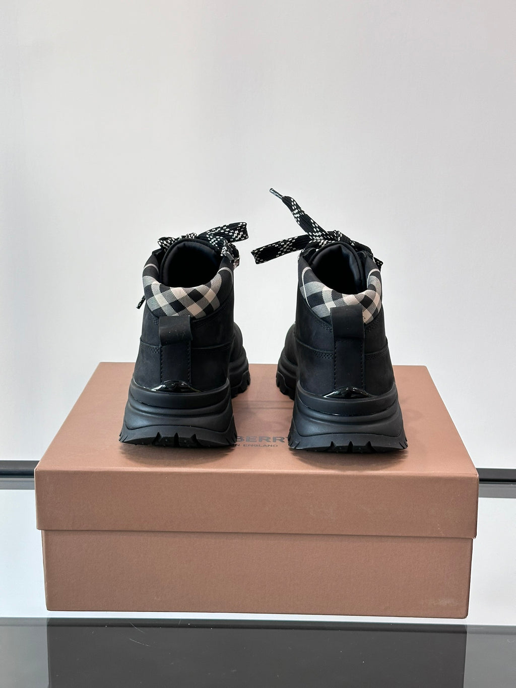Back view of black high-top lace-up boots with plaid lining and chunky sole