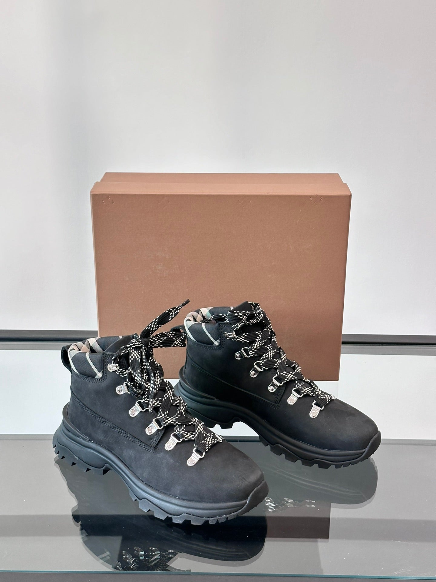 Black high-top lace-up boots with plaid-lined collar and thick outsole