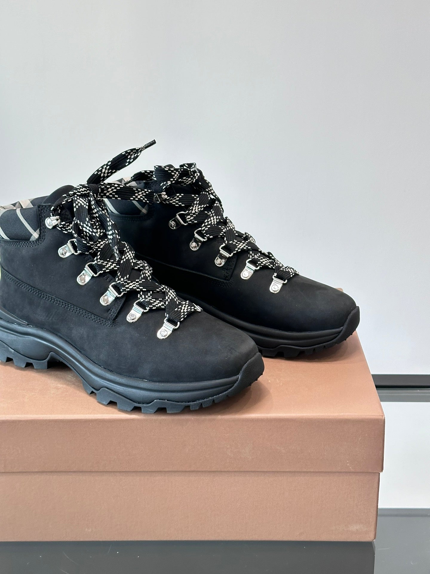 Close-up of black high-top lace-up boots with plaid collar and metal lace charms