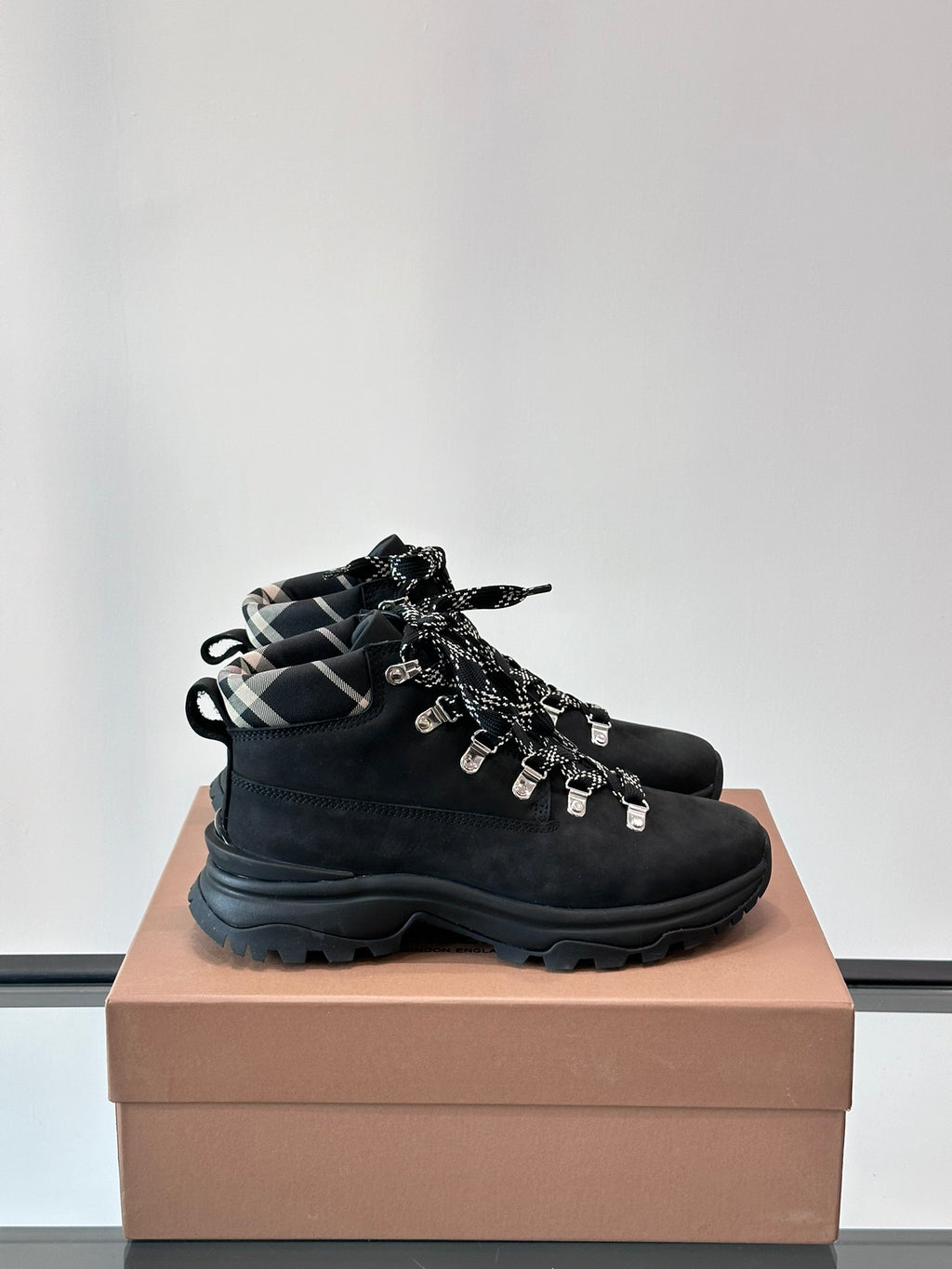 Black high-top lace-up boots with plaid-lined collar and chunky rubber sole