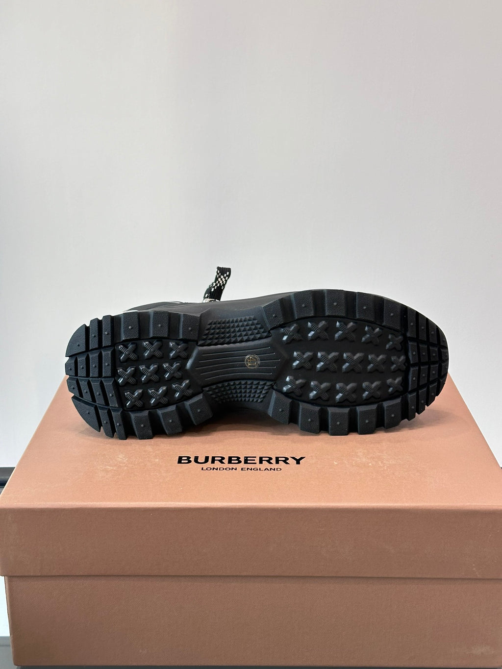 Outsole view of black high-top lace-up boots with deep lug tread