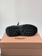 Outsole view of black high-top lace-up boots with deep lug tread