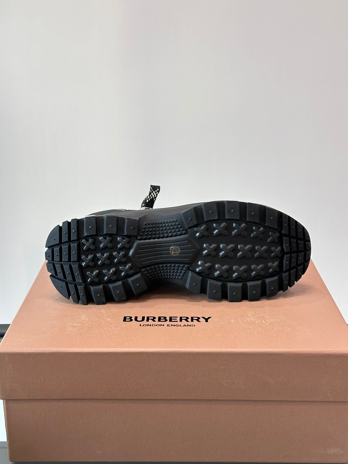 Outsole view of black high-top lace-up boots with deep lug tread