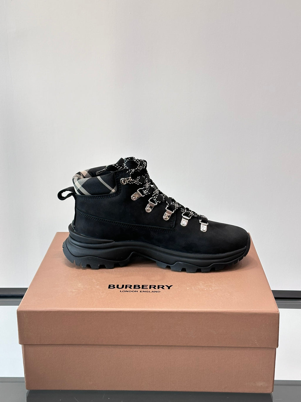 Black high-top lace-up boot with plaid-lined collar and silver lace hardware