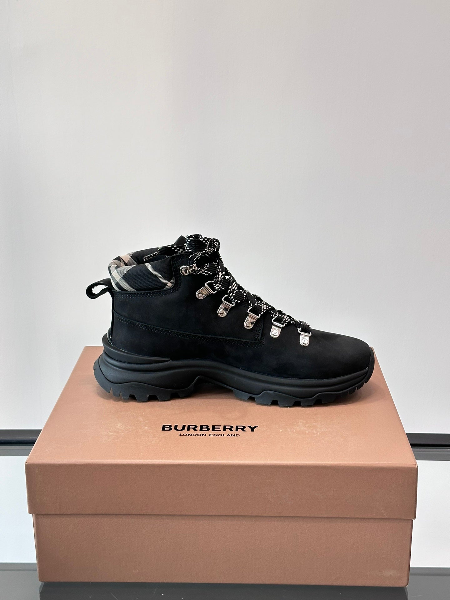 Black high-top lace-up boot with plaid-lined collar and silver lace hardware