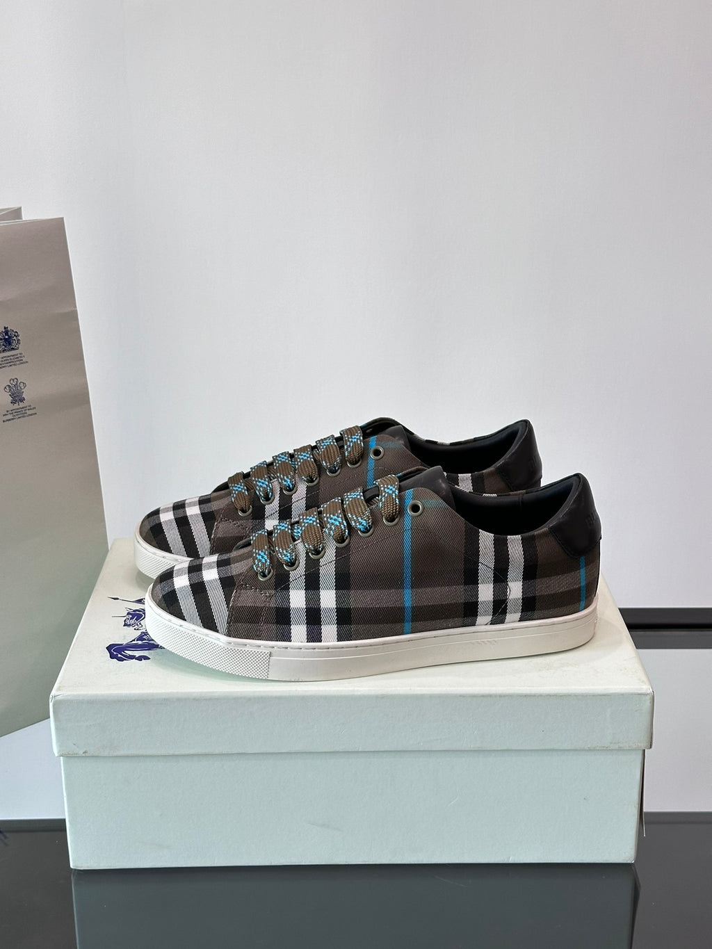 Plaid low-top sneakers on box, lace-up design with black trim and blue accents