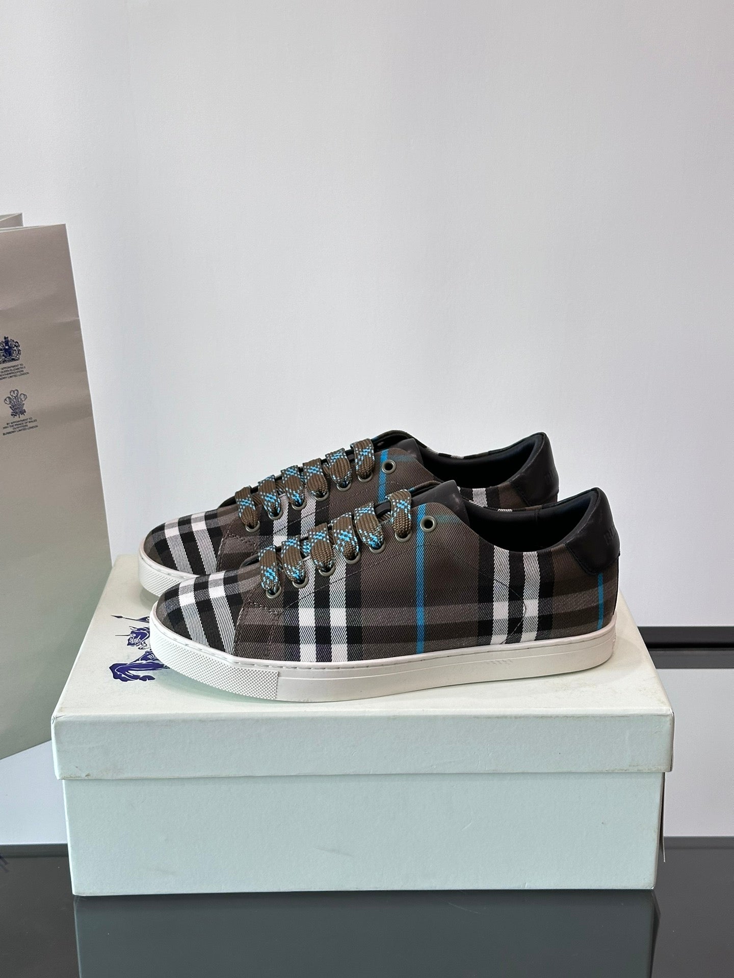 Plaid low-top sneakers on box, lace-up design with black trim and blue accents