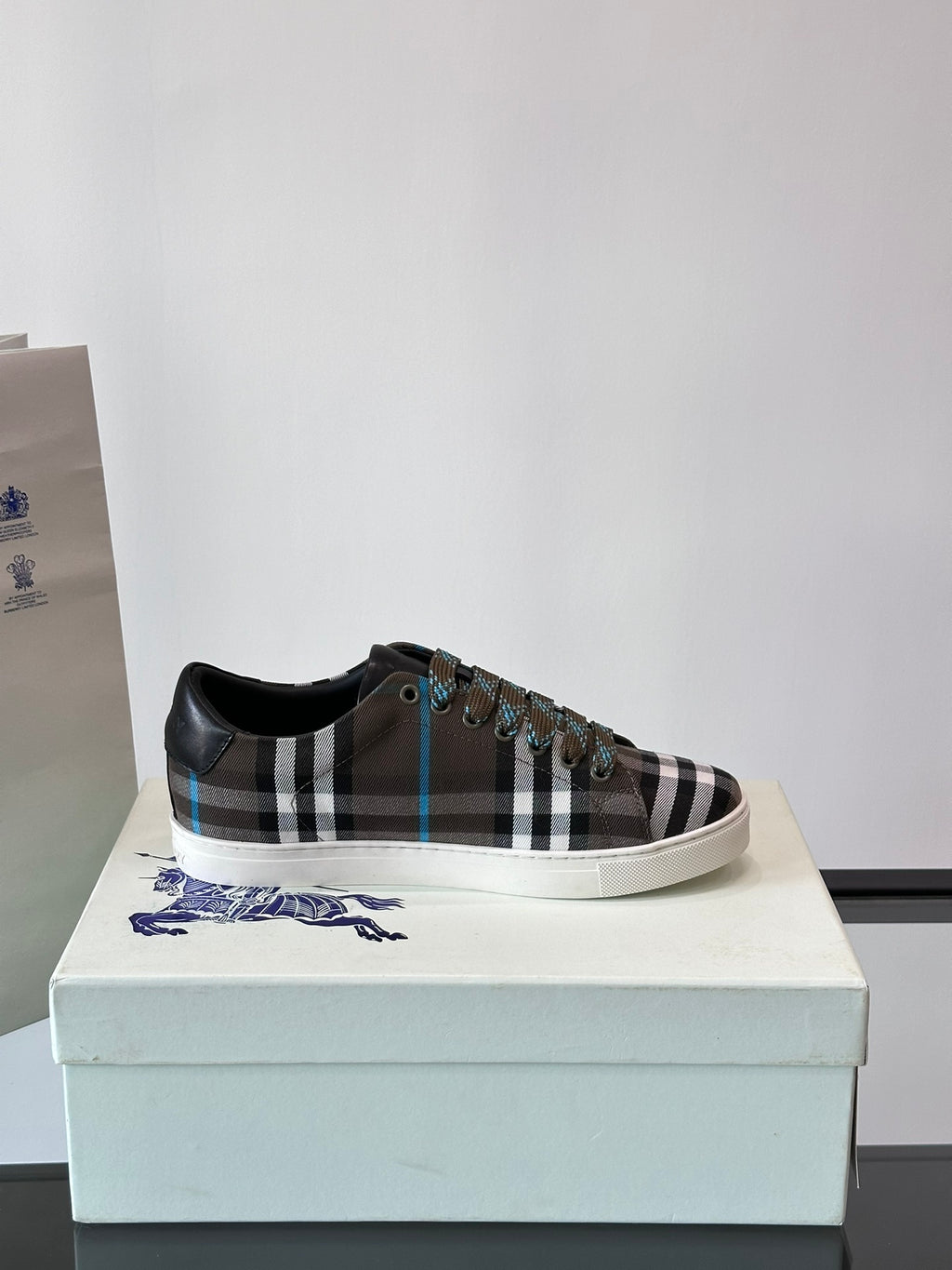 Plaid low-top sneaker on box, black trim, lace-up with blue accents