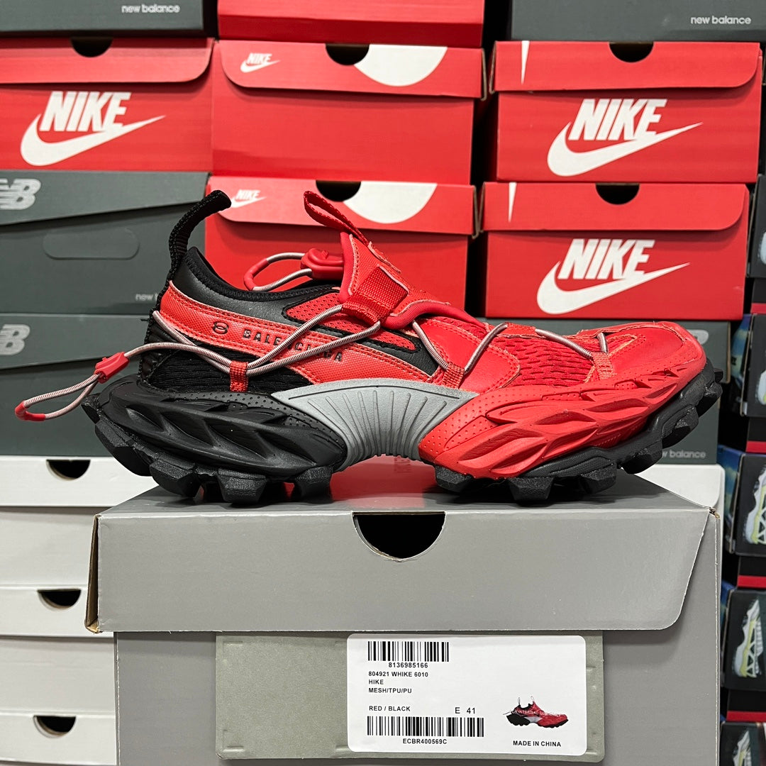 Red and black chunky sneaker on gray box, side view, lace-up