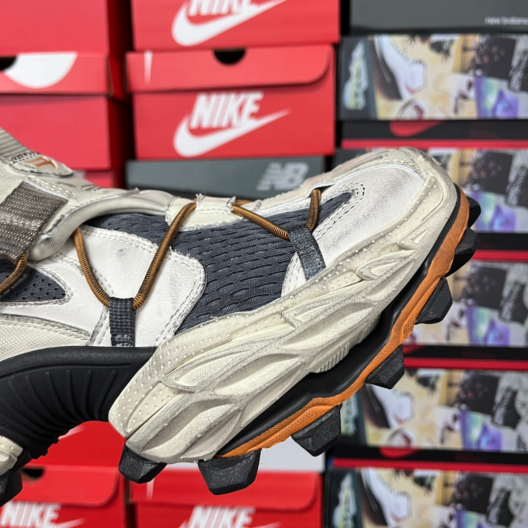 Balenciaga sneaker side with white/gray leather panels, black knit, and orange outsole edge.