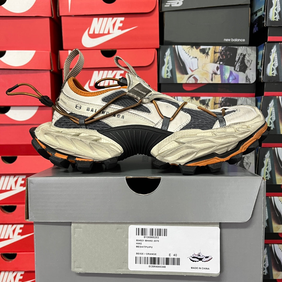 Balenciaga chunky lace-up sneakers in light gray and black with brown/orange lining, side view.
