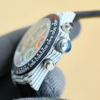 Rolex Daytona watch case side with crown and blue accent button.